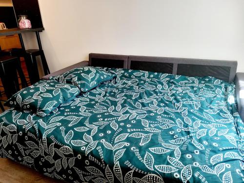 a bed with a green and white blanket and pillows at T3 Meublé 6 Couchages in Monein