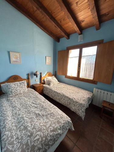 Casa Rural Amarilla في أفيلا: غرفة نوم بها سريرين ونافذة