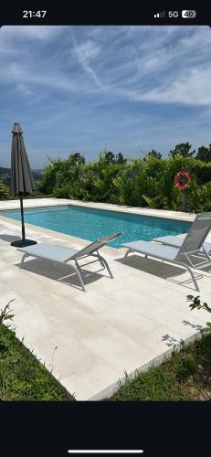 a swimming pool with two chairs and an umbrella at Quinta da Travessa in Cinfães