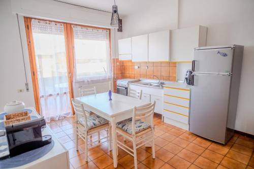 a kitchen with a table and a white refrigerator at San Giacomo Sweet Home in Nettuno