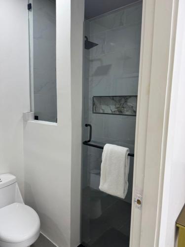 a bathroom with a toilet and a glass shower door at Hotel The Royalty Inn in Guayaquil