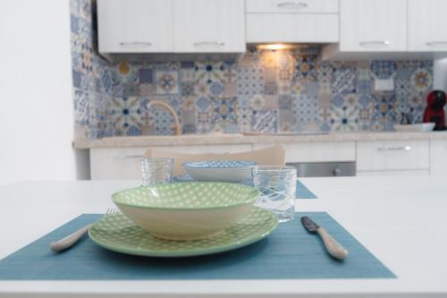 a kitchen table with a bowl and plates on it at Meucci Favignana Apartments in Favignana