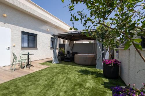 a backyard with a covered patio with a couch and a table at צימר נחלים - בקיבוץ הגושרים in Hagoshrim