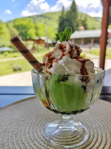 a glass bowl of ice cream with a stick in it at Pensiunea Pastravaria Vistisoara in Vistisoara