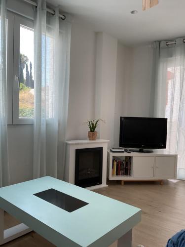 a white living room with a table and a tv at Casa en Salobreña, La Caleta, a 200m de la playa con garaje privado in Salobreña