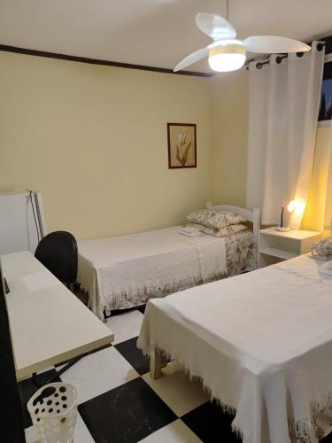 a room with two beds and a table and a lamp at Kzazendf Cama&Cafe Hospedagem Familiar in Brasilia