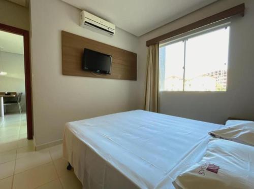 Un dormitorio con una cama y un televisor en la pared. en Equilibrio Hotel Veredas Flat - Rio Quente Goias, en Rio Quente