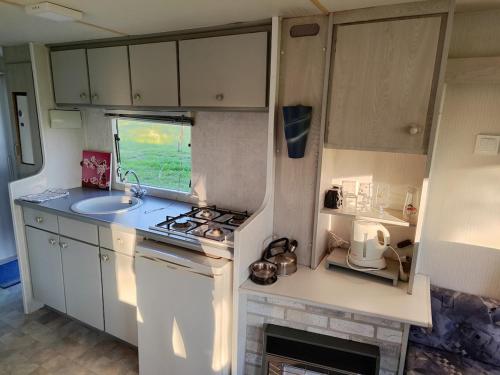 a small kitchen with a stove and a sink at Mobilhome Emil in Jiříkov