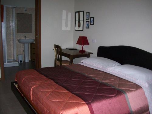 a bedroom with a bed and a desk with a lamp at La Bottega Del Falegname in Vanzaghello