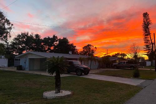 a palm tree in front of a house with a sunset at 1 Mi to Beach Nokomis Home with Private Pool in Nokomis