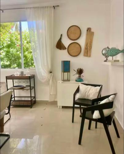 a living room with chairs and a table and a window at Villa Puntacana Village near by the airport and beach in Punta Cana