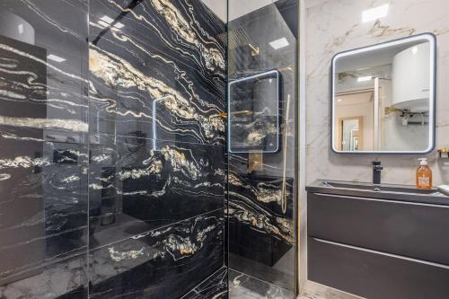 La salle de bains est pourvue d'un mur en marbre noir et or. dans l'établissement Appart 1 pièce pointe de la Croisette à cannes, à Cannes