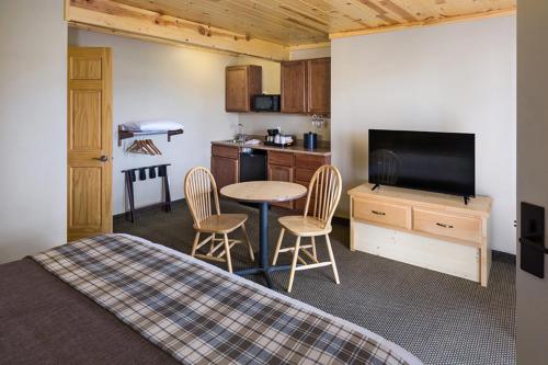 a bedroom with a bed and a table and a kitchen at Rock Crest Lodge & Cabins in Custer