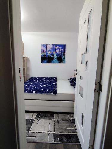 a small room with a bed with a painting on the wall at Perla Bocșei - Apartament Etaj 4 in Bocşa