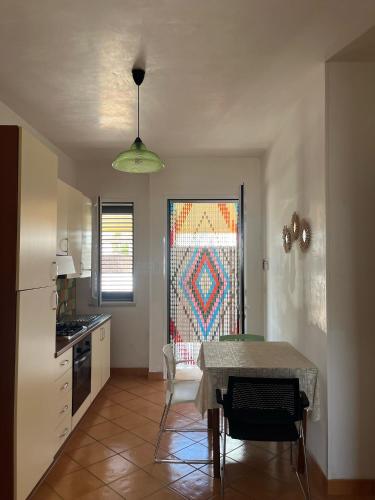 a kitchen with a table and a kitchen with a window at Casa vacanza relax a due passi dal mare in Marina di Mancaversa