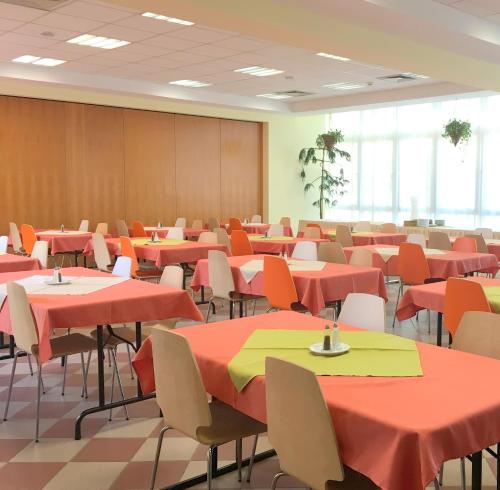 a room filled with tables and chairs with red and yellow tables at CEU Konferencia Központ in Budapest