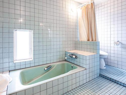 a bath tub in a bathroom with a window and a toilet at Sauna & Cottage SHIOJINO - Vacation STAY 06218v in Karatsu