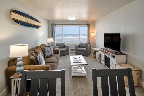 a living room with a couch and a tv at Oceanfront Suite - Upper Floor in Lincoln City