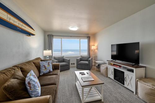 a living room with a couch and a flat screen tv at Oceanfront Suite - Upper Floor in Lincoln City