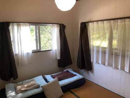 a bedroom with a bed and a window with curtains at Komorebi - Vacation STAY 19100 in Kuroshima