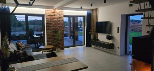 a living room with a couch and a tv in it at Forest Loft Kaszuby in Przytarnia