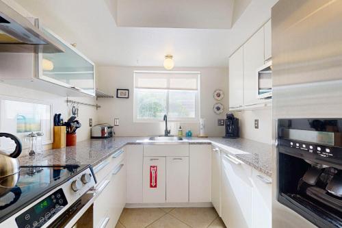 a kitchen with white cabinets and a large window at Oakmount Escape in Desert Hot Springs