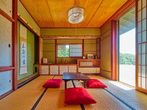 una stanza con un tavolo e dei cuscini rossi di Villa HANAMIZUKI - Vacation STAY 12012v a Kasama