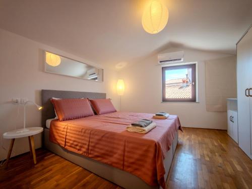 a bedroom with a bed with orange sheets and a window at Apartma Flora - Apartment Flora in Koper