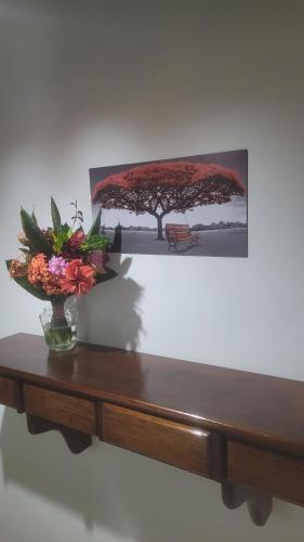 a table with a vase of flowers and a picture at Aconchego jacaroa in Maricá