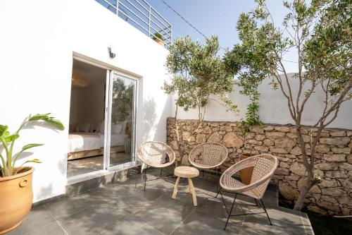 a patio with three chairs and a table and a wall at Ocean By La Siredrah in Wassane