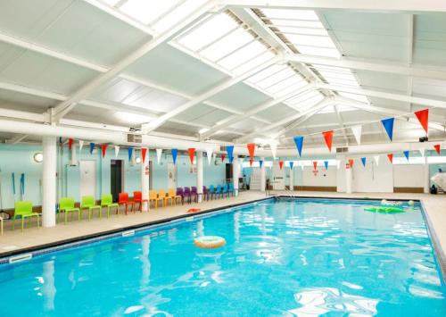 a swimming pool with blue water and colorful chairs at ABI Vista Caravan, Whitley Bay in Whitley Bay
