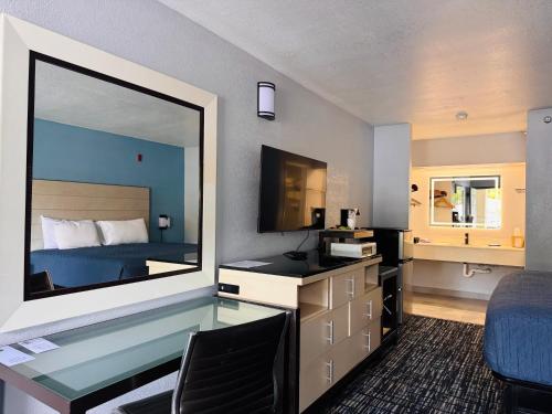 a hotel room with a glass desk and a bed at Wander Inn in Branson