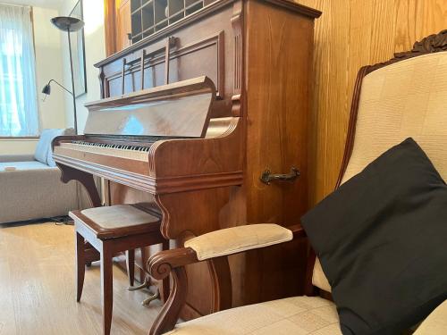 un piano dans une pièce avec une chaise et un canapé dans l'établissement Chez Mamie - 8 personnes - Familial - Confort - Parking public - Librairie, à Arras