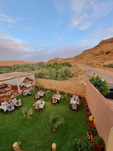 an outdoor patio with tables and chairs on the grass at Riad Sahara Stars Dades in Boumalne