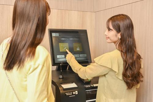a woman is pointing at a computer screen at Sanco Inn Grande Tokyo Hamamatsucho in Tokyo