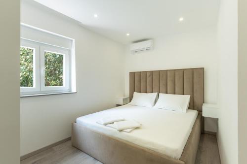 a white bedroom with a large bed with a window at Villa Marijo with a pool in Novalja