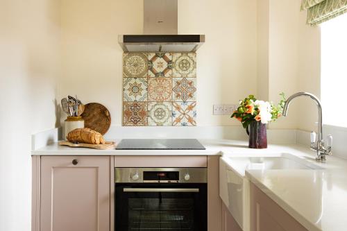 a kitchen with a sink and a stove at Wychwood Cottage in Charlbury