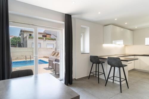 a kitchen and living room with a table and stools at Villa Marijo with a pool in Novalja