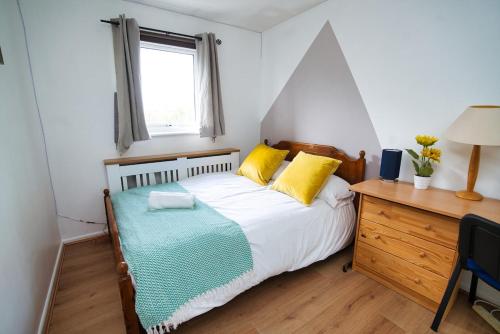 a bedroom with a bed with yellow pillows and a desk at Home close to city center home in Milton Keynes