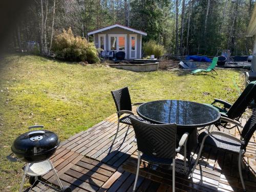 a table and chairs on a deck with a grill at DR ÅSA Apartment Penthouse w Pool by the Forest near a Golf course, Concerts and the Baltic Sea in Järna