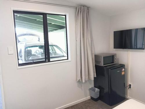 ロトルアにある1 Double Beds Serviced Studioのテレビ、窓、冷蔵庫が備わる客室です。