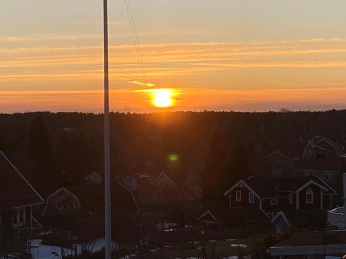 a sunset over a city with houses and a pole at DR ÅSA Apartment Penthouse w Pool by the Forest near a Golf course, Concerts and the Baltic Sea in Järna