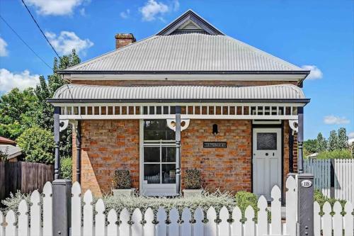 a brick house with a white picket fence at Prince Street Cottage - 1890’s Edwardian Gem in Orange