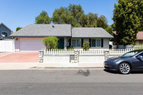 a car parked in front of a house with a white fence at Feel At Home In MV - 'Good Vibes Only' Mentality in Mission Viejo