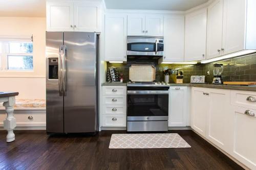 a kitchen with white cabinets and a stainless steel refrigerator at Feel At Home In MV - 'Good Vibes Only' Mentality in Mission Viejo