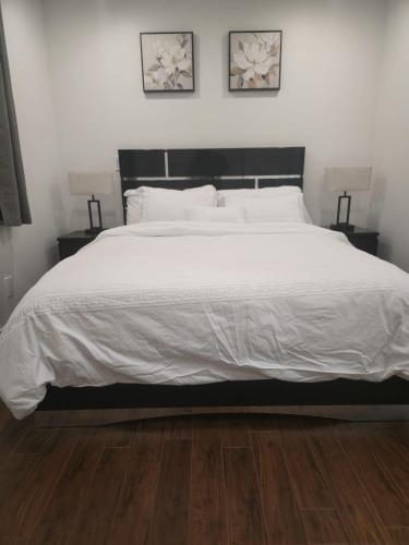 a bedroom with a large white bed with two lamps at Cozy & Spacious 1-Bedroom SW Calgary near SpruceMeadows in Calgary