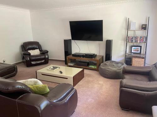 a living room with leather furniture and a flat screen tv at Fairhall Guest Lodge in Woodbourne