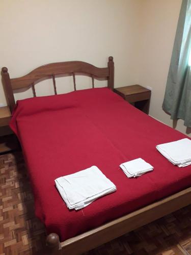 a bed with red sheets and white towels on it at Cabañas La FLorencia in Magdalena