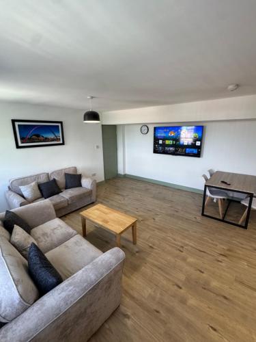 a living room with two couches and a table at CityWest Apartments in Newcastle upon Tyne