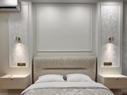 a white bedroom with a bed with two night stands at NBG d 'amore Appart in Batumi